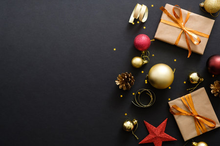 Modern red and golden Christmas decorations, baubles, gift boxes, confetti stars on dark black...