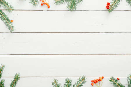Christmas minimal composition. Christmas frame made of fir tree branches on white wooden desk. Christmas, winter, new year concept. Flat lay, top view, copy spaceの写真素材