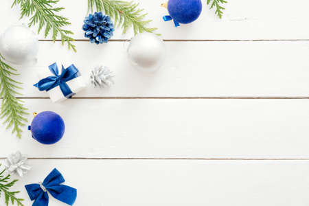 Christmas card with blue balls, fir tree branches, gift boxes, ornaments on wooden white background. New year holiday festive banner mockup. Christmas card template. Flat lay, top view, overheadの写真素材