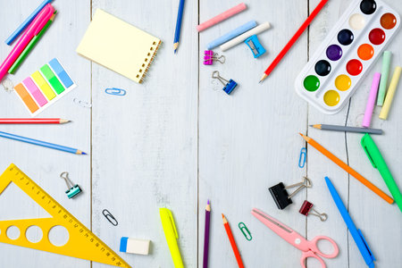School supplies stationery, color pencils, paints, paper on pastel blue wooden table, back to school...