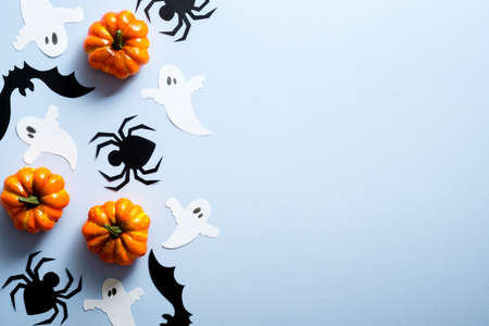 Happy halloween holiday concept. Halloween decorations, spiders, bats, ghosts, pumpkins on blue background. Halloween party greeting card mockup with copy space. Flat lay, top view, overhead.の写真素材