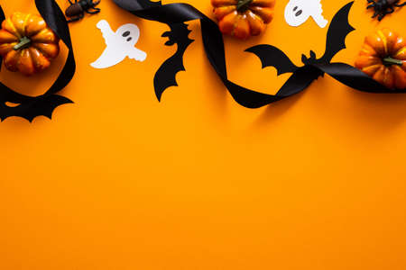 Happy halloween holiday concept. Halloween decorations, pumpkins, bats, ghosts on orange background. Halloween party greeting card mockup with copy space. Flat lay, top view, overhead.の写真素材