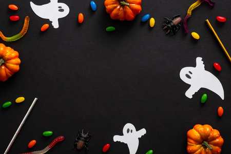 Halloween frame with pumpkins, ghosts, candy, ribbon on black background. Halloween party invitation...