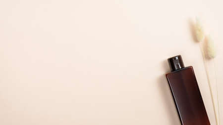 Natural cosmetic bottle container and dry flower on pastel beige background with copy space. Flat lay, top view. Eco friendly, organic product. Beauty and spa concept.の写真素材