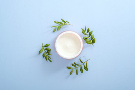 Moisturizing care skincare face cream for healing complicated troubled skin type in an open jar decorated eucalyptus leaves. Flat lay, top view, overhead. Skin care, beauty and healthcare concept.の写真素材