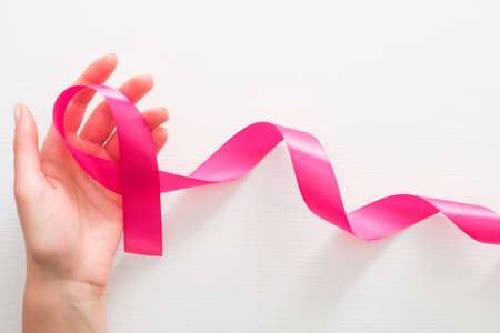 Female hands with pink ribbon as a symbol of the fight against breast cancer over white background. Breast cancer awareness month card. Healthcare and medicine conceptの写真素材