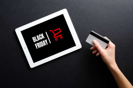 Black friday concept. Woman hand holding credit card and make payment online in E-commerce Shop page open in tabletの写真素材