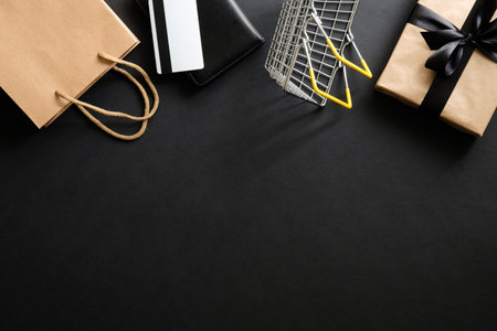 Black friday sale concept. Frame made of gift box, debit card, shopping bag and shopping cart over...