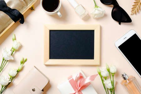 Female workspace with picture frame, smartphone, roses flowers, golden accessories, gift box, glasses, coffee cup. Flat lay women's office desk. Top view feminine background.の写真素材