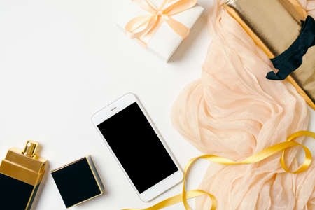 Fashion blogger workspace concept. Top view feminine background. Flat lay beauty blogger home office desk. Women's accessories, bag, scarf, gift box and mobile phone on white background.の写真素材