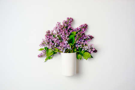Glass bottle with blooming lilac flowers over white background. Creative flat lay composition, top view, overhead. Spring flowers concept.の写真素材