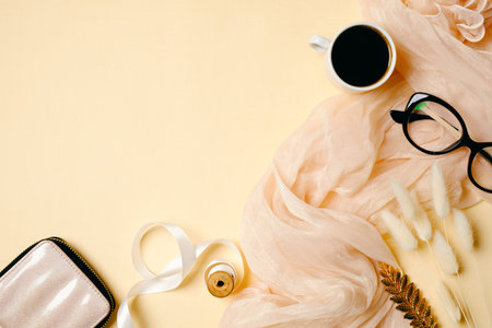 Woman home office desk with coffee cup, glasses, silk scarf and accessories on beige background. Flat lay beauty blogger workspace. Top view feminine background with copy space for your text.の写真素材