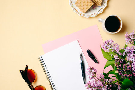 Flat lay home office desk. Female workspace with white paper notebook, glasses, coffee cup and lilac...