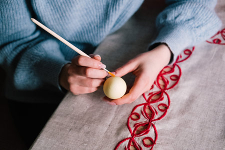Female hands painting easter egg with brush