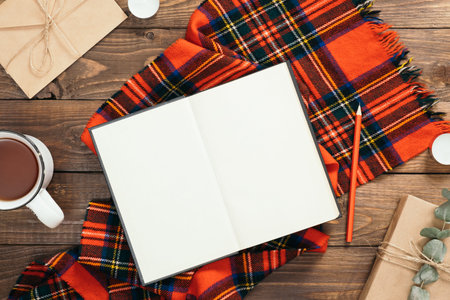 Autumn flatlay composition with red knitted scarf, blank book, cup of tea, craft envelope, pen, gift...