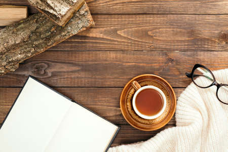 Autumn composition. Cup of tea, women fashion scarf, glasses, firewood on wooden background. Flat lay, top view, copy space. Scandinavian hygge concept.の写真素材