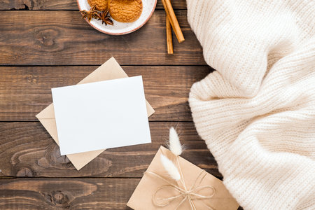 Autumn or winter flatlay composition with white wool plaid, blank paper card mockup, envelope,...