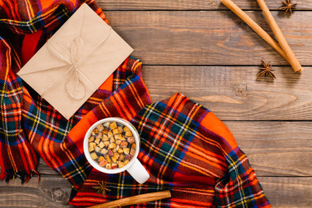 Flatlay autumn composition. Cup of tea, red plaid, vintage envelope, cinnamon stick on wooden...