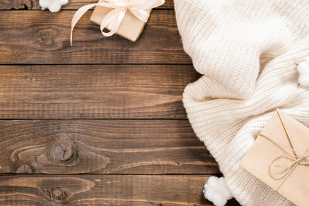 Autumn or winter composition. Women fashion sweater, gift box, craft paper envelope on rustic wooden...