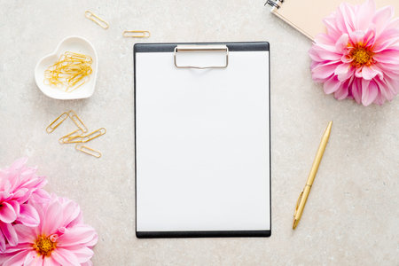 Flat lay home office desk. Female workspace with paper clipboard mockup, pink dahlia flowers, woman...