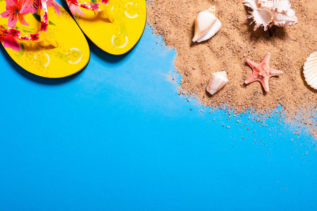 Summer vacation concept with seashells, starfish and women's beach sandals on a blue background and...