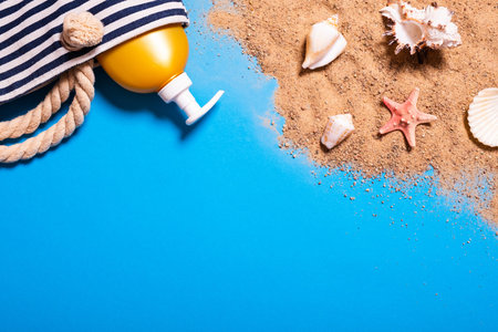 Summer vacation concept with seashells, starfish, women's beach bag and suntan lotion bottle on a...