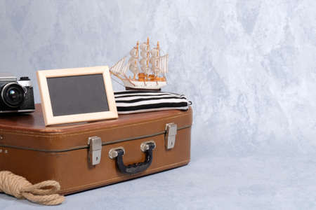 old fashioned leather suitcase, picture frame with blank black space for text, sailboat toy, retro photo camera, rope. Clothing and personal accessories of sailor, nautical and marine style conceptの写真素材