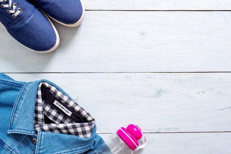 Stylish clothing look in flat lay style on blue pastel colored wooden desk. Sport clothes and...