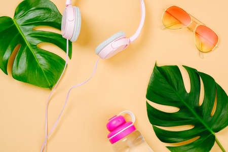 Top view feminine traveler stuff on yellow background. Minimal flat lay style composition with headphones, sunglasses, tropical monstera leaves and water bottle. Summer background, vacation conceptの写真素材