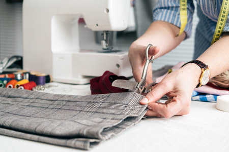 Tailor cutting jeans with scissors at workshop