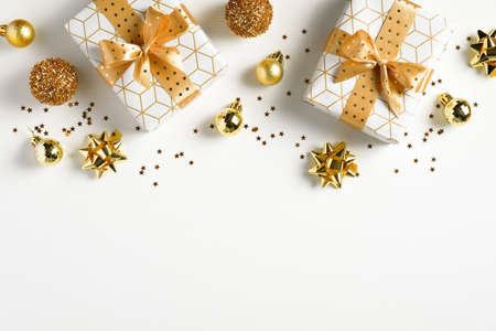 Christmas frame top border made of gift boxes, luxury golden decorations, stars, confetti on white background. Xmas greeting card, New year banner mockup. Flat lay, top viewの写真素材