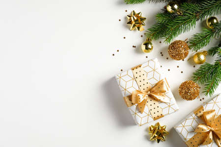 Christmas tree branches decorated golden balls, gift boxes, confetti on white background. Flat lay, top view. Xmas banner mockup with copy spaceの写真素材