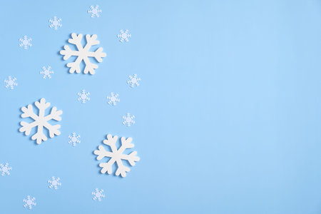 Christmas composition. Frame border of white snowflakes and confetti on blue background. Flat lay,...