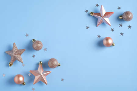 Christmas flat lay composition. Frame made of pink stars, baubles decorations, confetti on blue background. Christmas, winter, new year conceptの写真素材