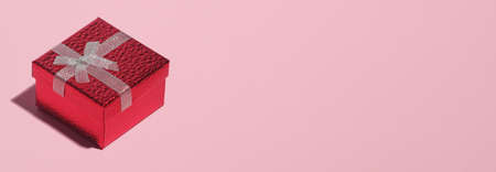 Red gift box with white ribbon bow on pastel pink background with copy space. Christmas banner mockup, header design, greeting card template.の写真素材