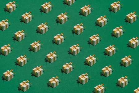 Pattern of white gift boxes with golden ribbon bow on green background. Vintage style. Christmas presents.の写真素材