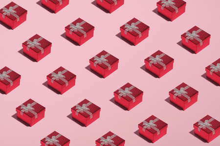 Pattern of red gift boxes on pink background. Christmas, New Year or Birthday celebration concept.の写真素材