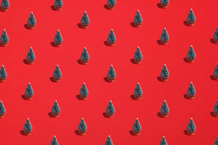 Pattern background of green Christmas trees on red. Xmas, New Year, winter holidays concept. Flat lay, top view.の写真素材
