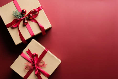 Gift boxes with red ribbon bow on marsala red background with copy space. Christmas presents, gift boxes, surprises concept. Flat lay, top view.の写真素材