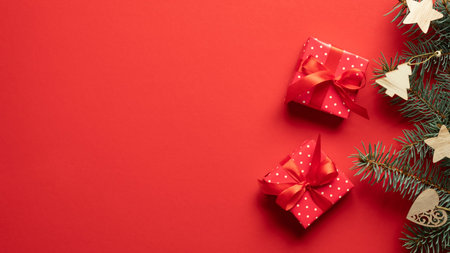 Gift boxes and fir branches with wooden Christmas decorations on red background. Christmas banner...