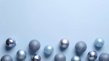 Christmas frame border made of blue and silver balls decoration on pastel blue background. Flat lay, top view. Christmas greeting card template, banner mockup.の写真素材