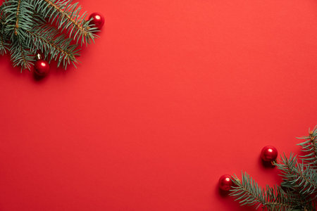 Christmas tree branches and red balls decoration on red background. Christmas greeting card, frame, banner mockup. Flat lay, top view, copy space.の写真素材