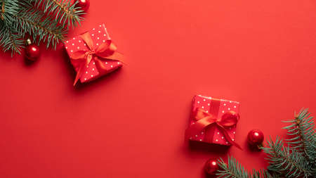 Christmas composition. Gift boxes, Christmas decorations and fir tree branches on red background. Flat lay, top view.の写真素材