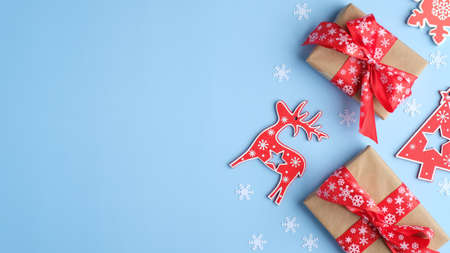 Vintage Christmas composition. Handmade gift boxes and red Christmas decorations on blue background. Flat lay, top view, copy space. Xmas banner mockup.の写真素材