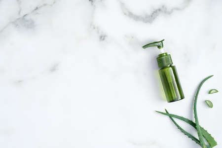 Aloe vera moisturizing gel bottle and sliced plant stems on marble background. Natural organic cosmetics for hands skin care and beauty treatment concept. Flat lay, top viewの写真素材