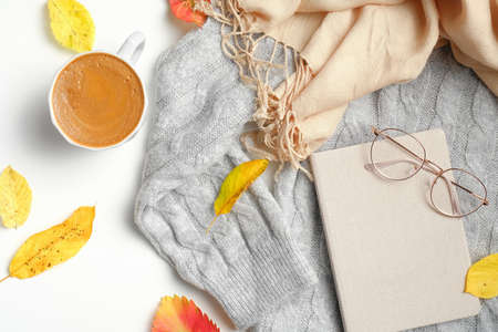 Autumn composition. Cup of coffee, gray sweater, beige female scarf, fallen leaves, paper notebook, glasses on white background. Autumn, fall concept. Flat lay, top view.の写真素材