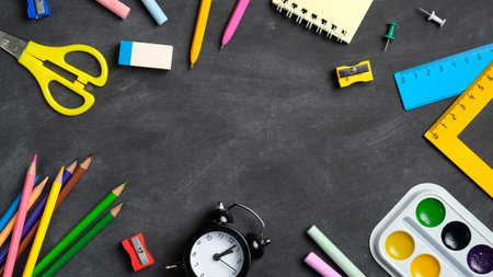 Frame of colorful school supplies on black board background. Flat lay, top view, overhead. Back to...