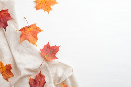 Autumn frame made of colorful maple leaves and beige fabric on white background. Minimalist style...