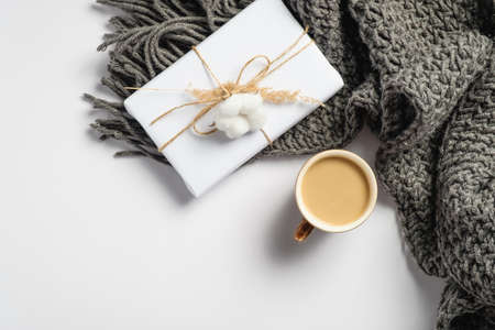 Cup of coffee, gift box and knitted scarf on white background. Hygge style flat lay composition, autumn fall concept. Top view cozy home desk.の写真素材