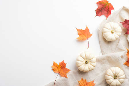 Autumn background with dry maple leaves, pumpkins, beige fabric. Minimal flat lay style composition, top view. Autumn comfort, hygge concept.の写真素材